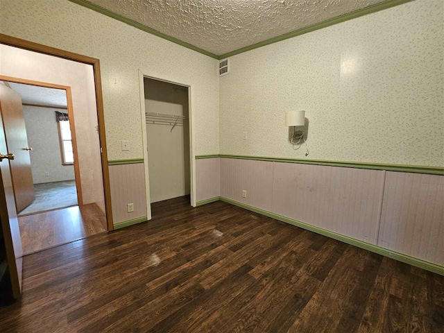 394 Townline Rd, Pellston, MI 49769 - unfurnished bedroom featuring wood finished floors, wainscoting, a textured ceiling, crown molding, and a closet