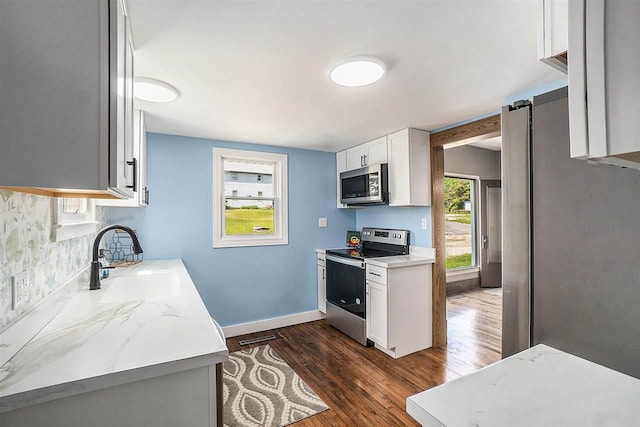 5791 Lebaron St, Levering, MI 49755 - kitchen with stainless steel appliances, a sink, dark wood finished floors, white cabinetry, and baseboards
