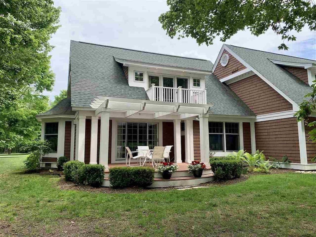 4162 Pinehurst Ln Unit 29, Harbor Springs, MI 49740 - rear view of property featuring a shingled roof, a yard, a balcony, and a patio area
