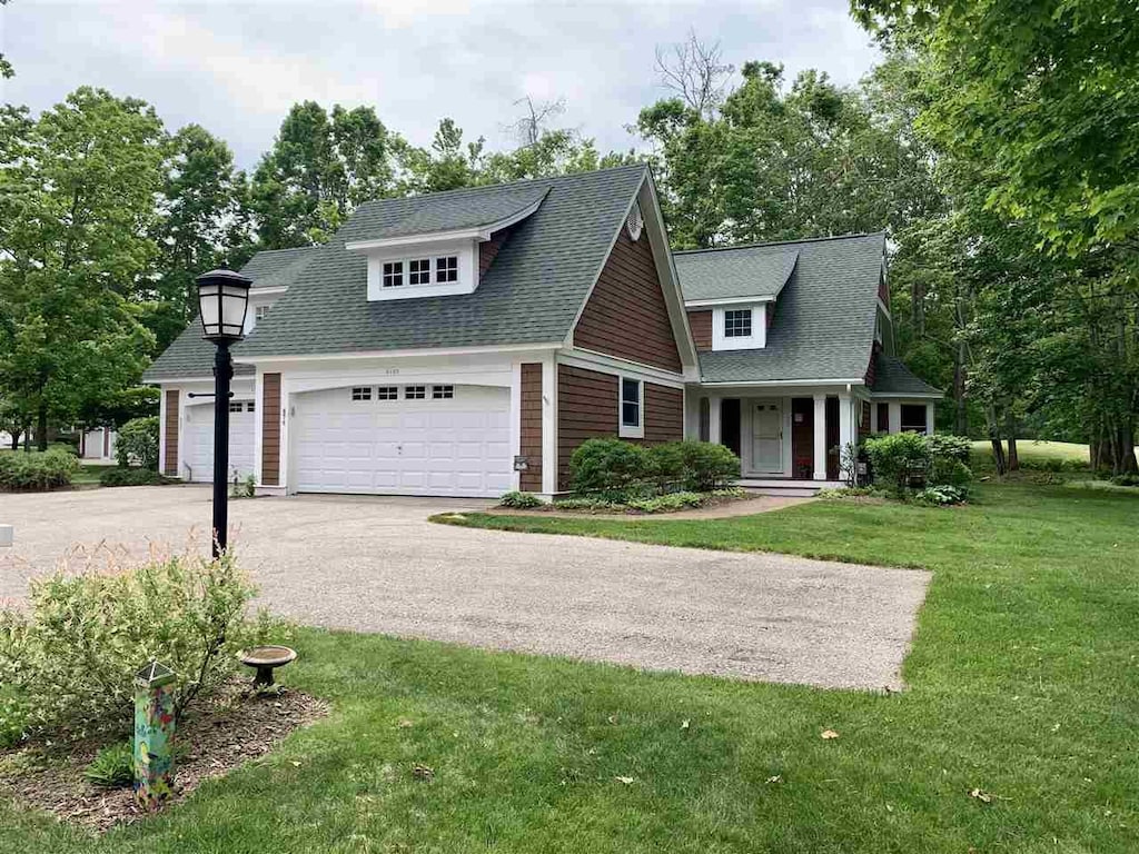 4162 Pinehurst Ln Unit 29, Harbor Springs, MI 49740 - view of front facade with a front yard, asphalt driveway, an attached garage, and roof with shingles