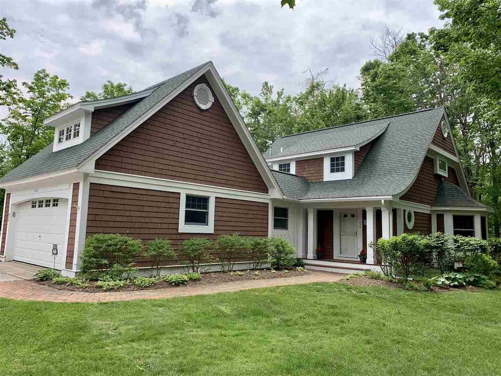 4162 Pinehurst Ln Unit 29, Harbor Springs, MI 49740 - view of front of house featuring a front yard, roof with shingles, and a garage
