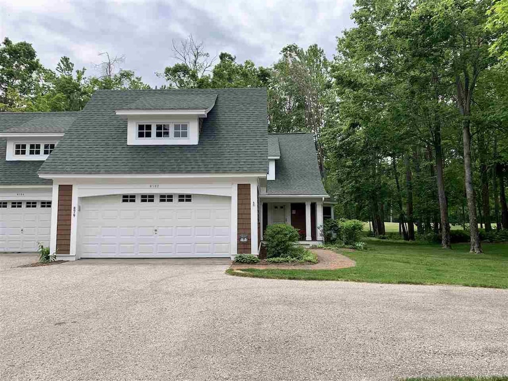 4162 Pinehurst Ln Unit 29, Harbor Springs, MI 49740 - view of front of house with driveway, a garage, a front lawn, and a shingled roof