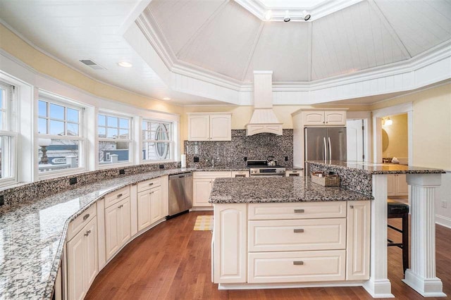 195 E Main St Unit 5, Harbor Springs, MI 49740 - kitchen featuring appliances with stainless steel finishes, dark stone counters, ornamental molding, a kitchen bar, and wood finished floors