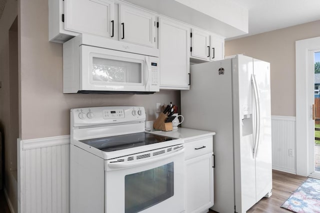 1105 Grant St, Charlevoix, MI 49720 - kitchen featuring white appliances, wainscoting, light countertops, white cabinets, and light wood-style floors