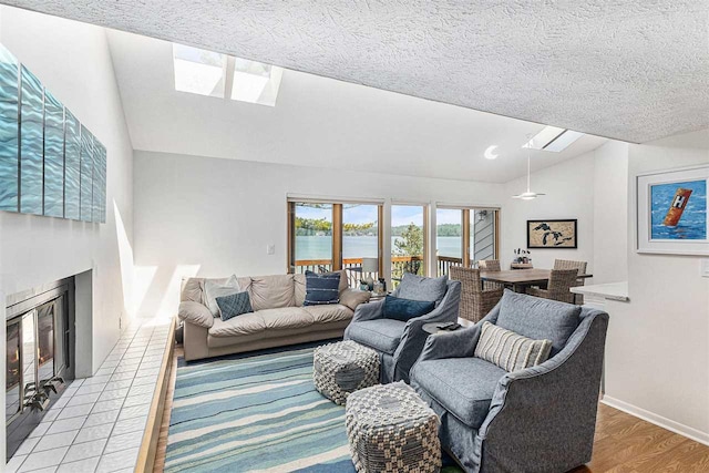 3480 Lakeside Dr N Unit 35, Petoskey, MI 49770 - living room featuring a skylight, lofted ceiling, a glass covered fireplace, a water view, and a textured ceiling
