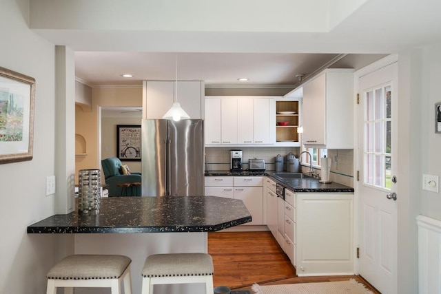 1029 Howard St, Petoskey, MI 49770 - kitchen featuring freestanding refrigerator, a sink, white cabinetry, decorative backsplash, and a peninsula