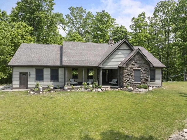 1367 Zink Rd, Boyne City, MI 49712 - view of front of house with a front yard, stone siding, a shingled roof, and a chimney