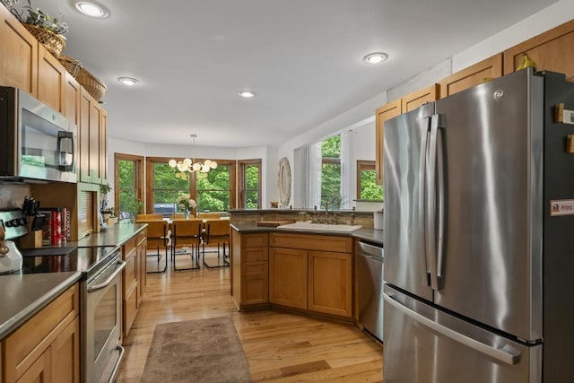 1367 Zink Rd, Boyne City, MI 49712 - kitchen with appliances with stainless steel finishes, a sink, dark countertops, light wood finished floors, and a peninsula