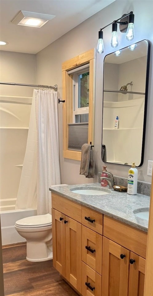 8512 Dutchman Bay Rd, East Jordan, MI 49727 - bathroom featuring wood finished floors, double vanity, toilet, and shower / tub combo with curtain