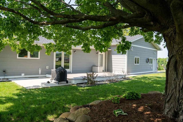 8512 Dutchman Bay Rd, East Jordan, MI 49727 - rear view of house featuring a lawn, a wooden deck, a patio area, and roof with shingles