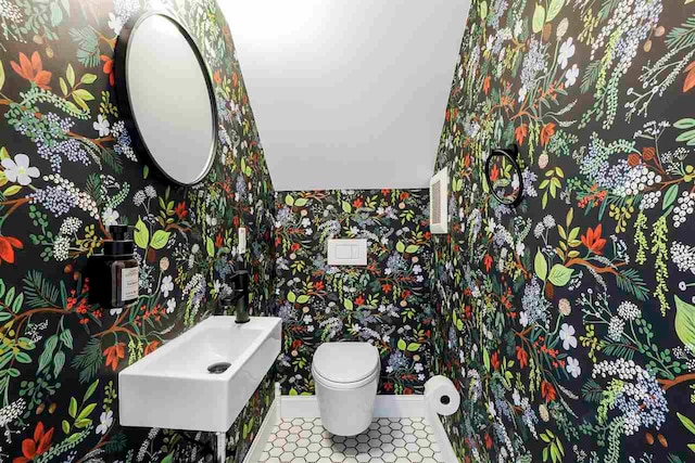 503 N Bridge St, Bellaire, MI 49615 - half bathroom with wallpapered walls, toilet, a sink, and tile patterned floors