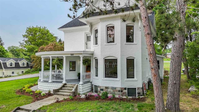 503 N Bridge St, Bellaire, MI 49615 - view of front facade featuring covered porch, brick siding, and a front yard