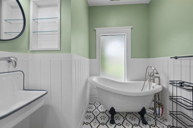 503 N Bridge St, Bellaire, MI 49615 - bathroom featuring wainscoting, a freestanding bath, and tile patterned floors