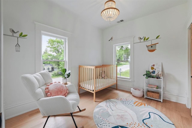 503 N Bridge St, Bellaire, MI 49615 - bedroom featuring a chandelier, wood finished floors, and a crib