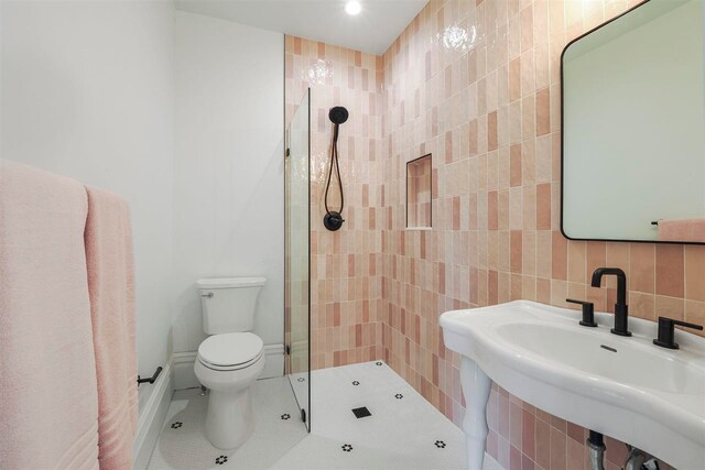 503 N Bridge St, Bellaire, MI 49615 - bathroom featuring a sink, tile walls, toilet, a tile shower, and tile patterned flooring