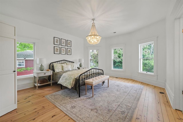 503 N Bridge St, Bellaire, MI 49615 - bedroom featuring light wood-style floors, a chandelier, multiple windows, and baseboards