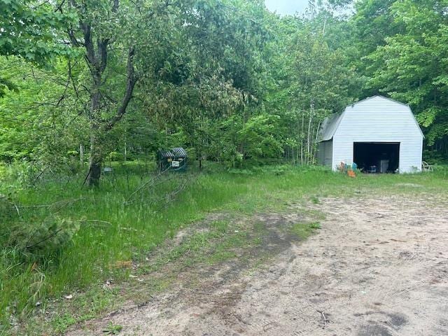 9540 Pickerel Lake Rd, Petoskey, MI 49770 - view of yard featuring a garage, an outdoor structure, and a wooded view