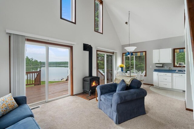 15700 Island Dr, Wolverine, MI 49799 - living area with a towering ceiling, light colored carpet, a water view, and a wood stove