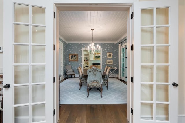 145 Traverse St, Harbor Springs, MI 49740 - dining room with wallpapered walls, crown molding, a chandelier, dark wood-type flooring, and french doors