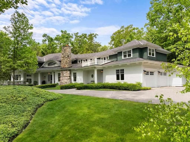 145 Traverse St, Harbor Springs, MI 49740 - shingle-style home with a front lawn, concrete driveway, a chimney, an attached garage, and a balcony