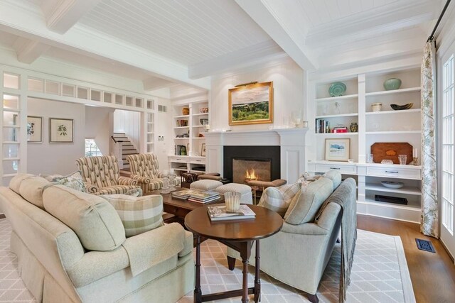 145 Traverse St, Harbor Springs, MI 49740 - living area with beamed ceiling, ornamental molding, a warm lit fireplace, wood finished floors, and built in shelves