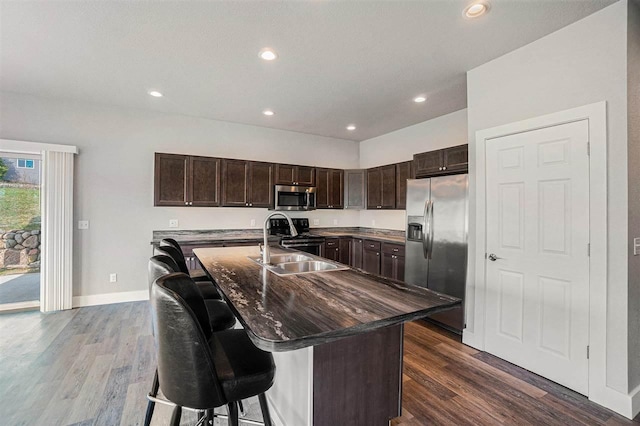 705 Maple Crk, Petoskey, MI 49770 - kitchen featuring appliances with stainless steel finishes, dark brown cabinetry, dark wood-style floors, a breakfast bar area, and an island with sink