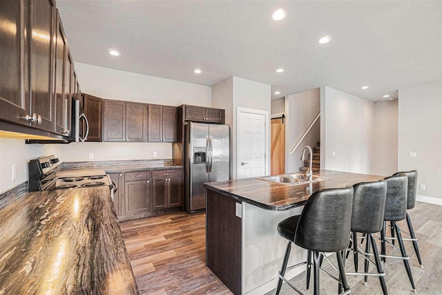 705 Maple Crk, Petoskey, MI 49770 - kitchen with appliances with stainless steel finishes, light wood-style floors, dark countertops, a breakfast bar, and dark brown cabinets