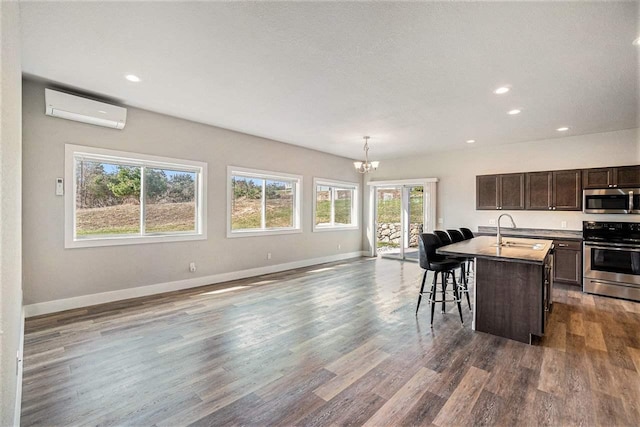 705 Maple Crk, Petoskey, MI 49770 - kitchen featuring stainless steel appliances, a wall unit AC, open floor plan, a chandelier, and healthy amount of natural light