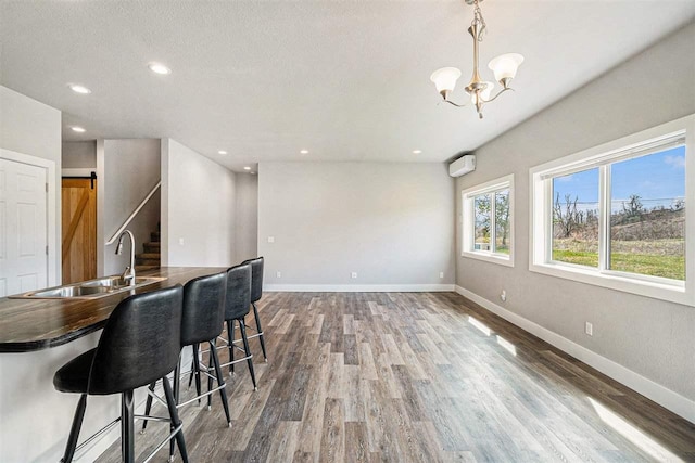 705 Maple Crk, Petoskey, MI 49770 - kitchen featuring wood finished floors, dark countertops, a chandelier, a wall mounted AC, and recessed lighting
