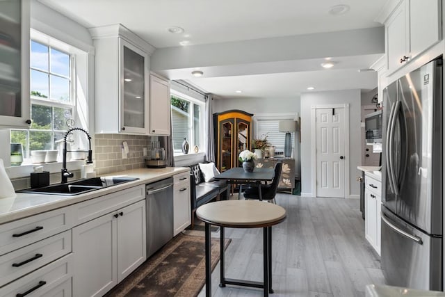 1116 N Lake St, Boyne City, MI 49712 - kitchen featuring stainless steel appliances, light countertops, wood finished floors, tasteful backsplash, and white cabinetry