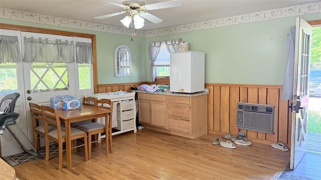 2160 Kladder Rd, Bellaire, MI 49615 - dining room with wainscoting, light wood finished floors, a ceiling fan, and a wall unit AC