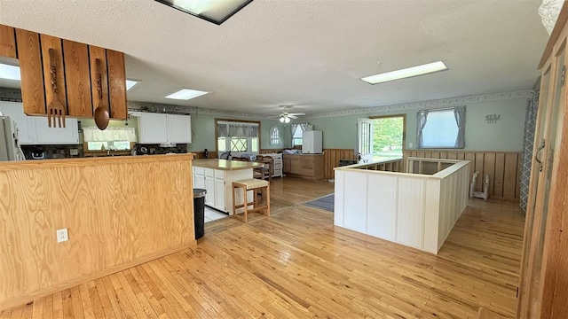 2160 Kladder Rd, Bellaire, MI 49615 - kitchen featuring light wood finished floors, a wainscoted wall, ceiling fan, healthy amount of natural light, and a peninsula