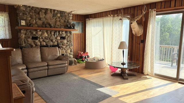 2160 Kladder Rd, Bellaire, MI 49615 - living room with wood finished floors, wooden walls, a large fireplace, and a textured ceiling
