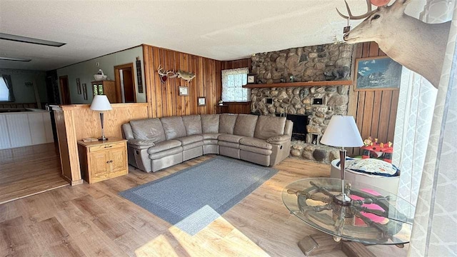 2160 Kladder Rd, Bellaire, MI 49615 - living area with wood finished floors, wood walls, a textured ceiling, and a stone fireplace