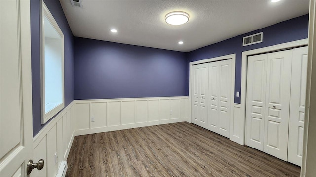 6069 Hills Cottage Ct Unit 5, Bay Harbor, MI 49770 - unfurnished bedroom with wood finished floors, wainscoting, two closets, recessed lighting, and a textured ceiling