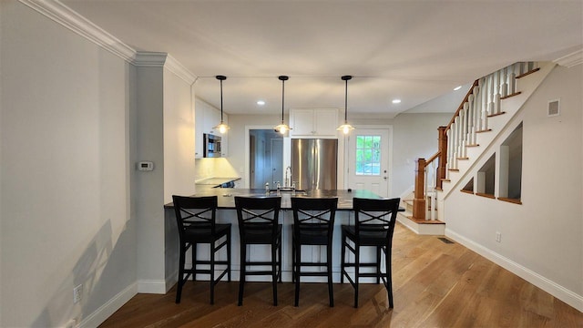 6069 Hills Cottage Ct Unit 5, Bay Harbor, MI 49770 - kitchen featuring stainless steel appliances, white cabinetry, a peninsula, a breakfast bar area, and wood finished floors