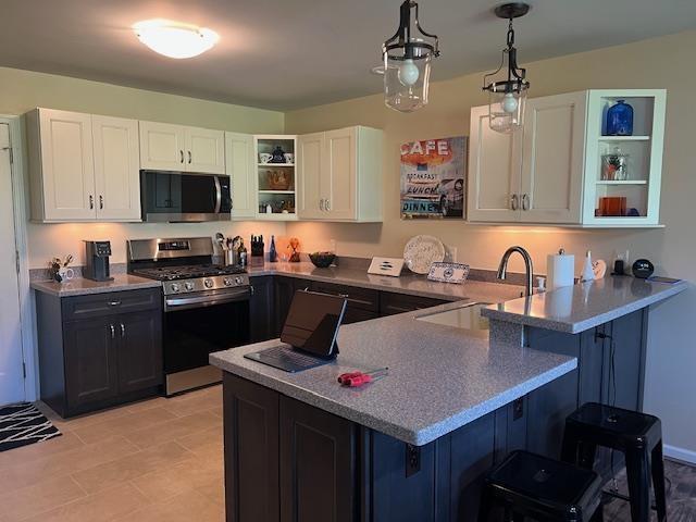 700 Fairways Dr Unit 14, Harbor Springs, MI 49740 - kitchen featuring stainless steel gas stove, open shelves, a breakfast bar area, and white cabinetry