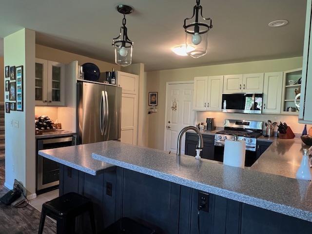 700 Fairways Dr Unit 14, Harbor Springs, MI 49740 - kitchen with stainless steel appliances, beverage cooler, a peninsula, glass insert cabinets, and white cabinetry