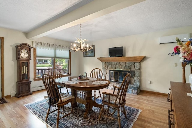 6989 Meadowlark Way, Gaylord, MI 49735 - dining room featuring a wall mounted AC, a baseboard heating unit, light wood-style floors, a stone fireplace, and a textured ceiling