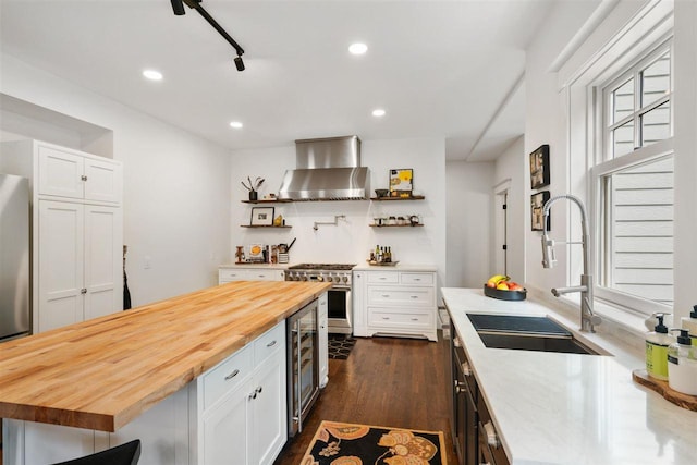 606 State St, Petoskey, MI 49770 - kitchen with high end range, wall chimney exhaust hood, wood counters, wine cooler, and white cabinetry