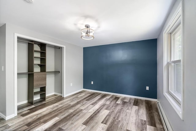 3049 Chippewa Beach Rd, Indian River, MI 49749 - unfurnished bedroom with a baseboard radiator, wood finished floors, and a closet
