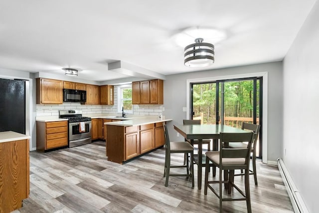 3049 Chippewa Beach Rd, Indian River, MI 49749 - kitchen with stainless steel range with gas cooktop, a baseboard heating unit, black microwave, and brown cabinets