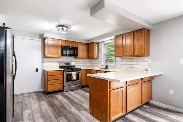 3049 Chippewa Beach Rd, Indian River, MI 49749 - kitchen featuring appliances with stainless steel finishes, a peninsula, tasteful backsplash, and wood finished floors