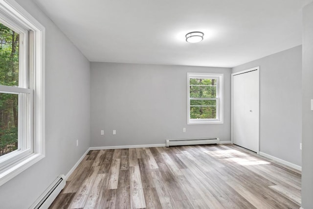 3049 Chippewa Beach Rd, Indian River, MI 49749 - unfurnished bedroom featuring a baseboard heating unit, wood finished floors, and a closet