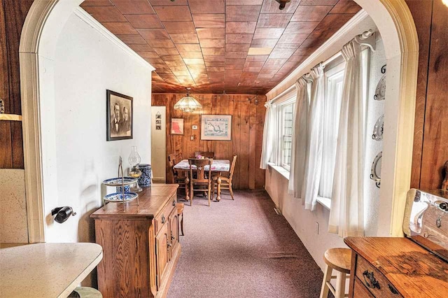 5272 Indian Garden Rd, Petoskey, MI 49770 - carpeted dining space with arched walkways, wooden walls, and ornamental molding