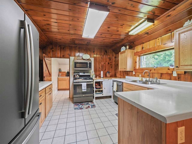 1922 Freeman Rd, East Jordan, MI 49727 - kitchen featuring appliances with stainless steel finishes, wood walls, light countertops, light tile patterned floors, and a peninsula