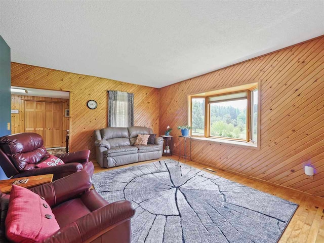 1922 Freeman Rd, East Jordan, MI 49727 - living area with wood-type flooring, wooden walls, and a textured ceiling