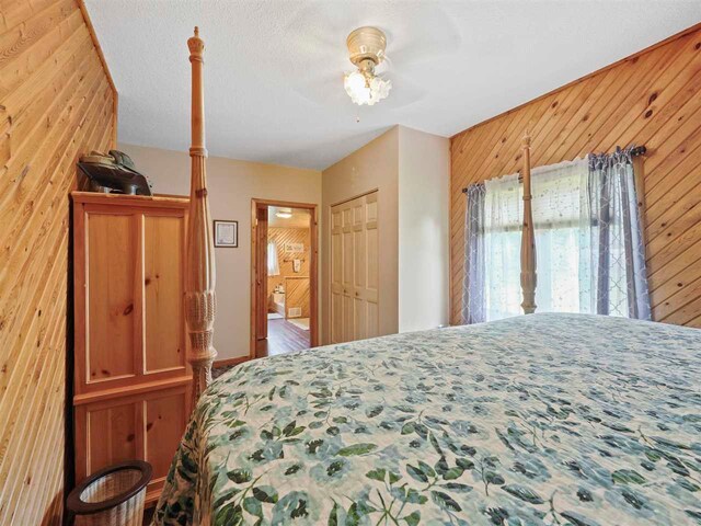 1922 Freeman Rd, East Jordan, MI 49727 - bedroom with wooden walls, a ceiling fan, and connected bathroom