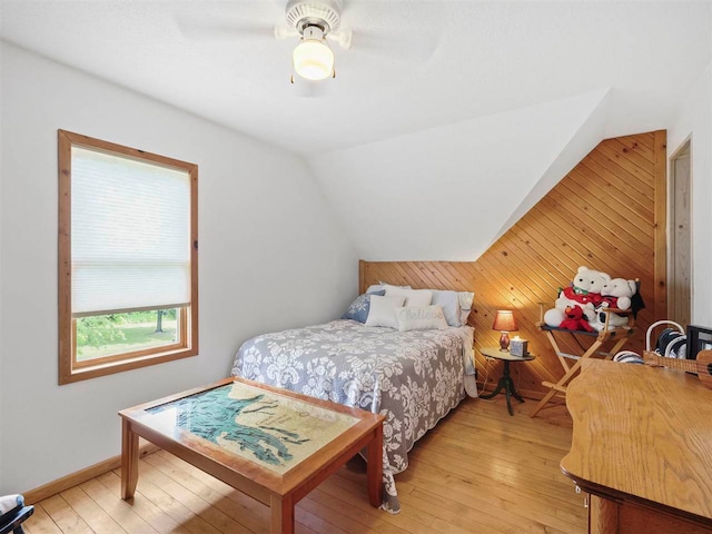 1922 Freeman Rd, East Jordan, MI 49727 - bedroom featuring wood walls, vaulted ceiling, light wood-style flooring, and a ceiling fan