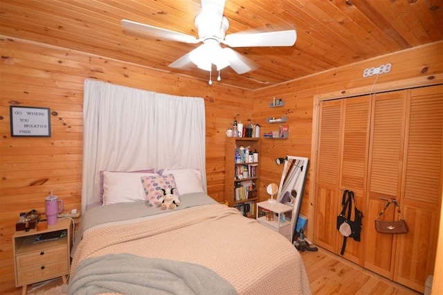 1340 Zink Rd, Boyne City, MI 49712 - bedroom featuring light wood-style floors, wooden walls, a closet, wooden ceiling, and ceiling fan